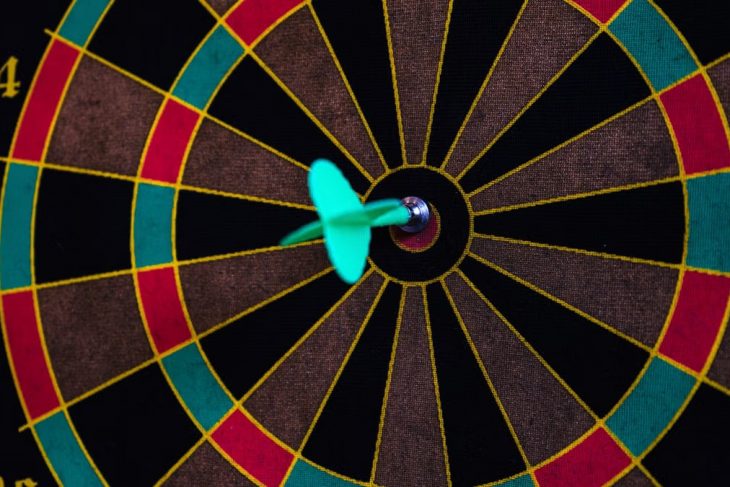 A vibrant close-up of a dart hitting the bullseye on a colorful dartboard, showcasing precision.